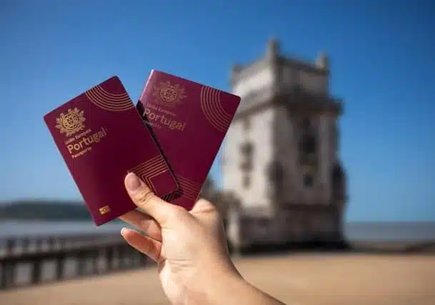 A person holding a Portuguese passport near a tower